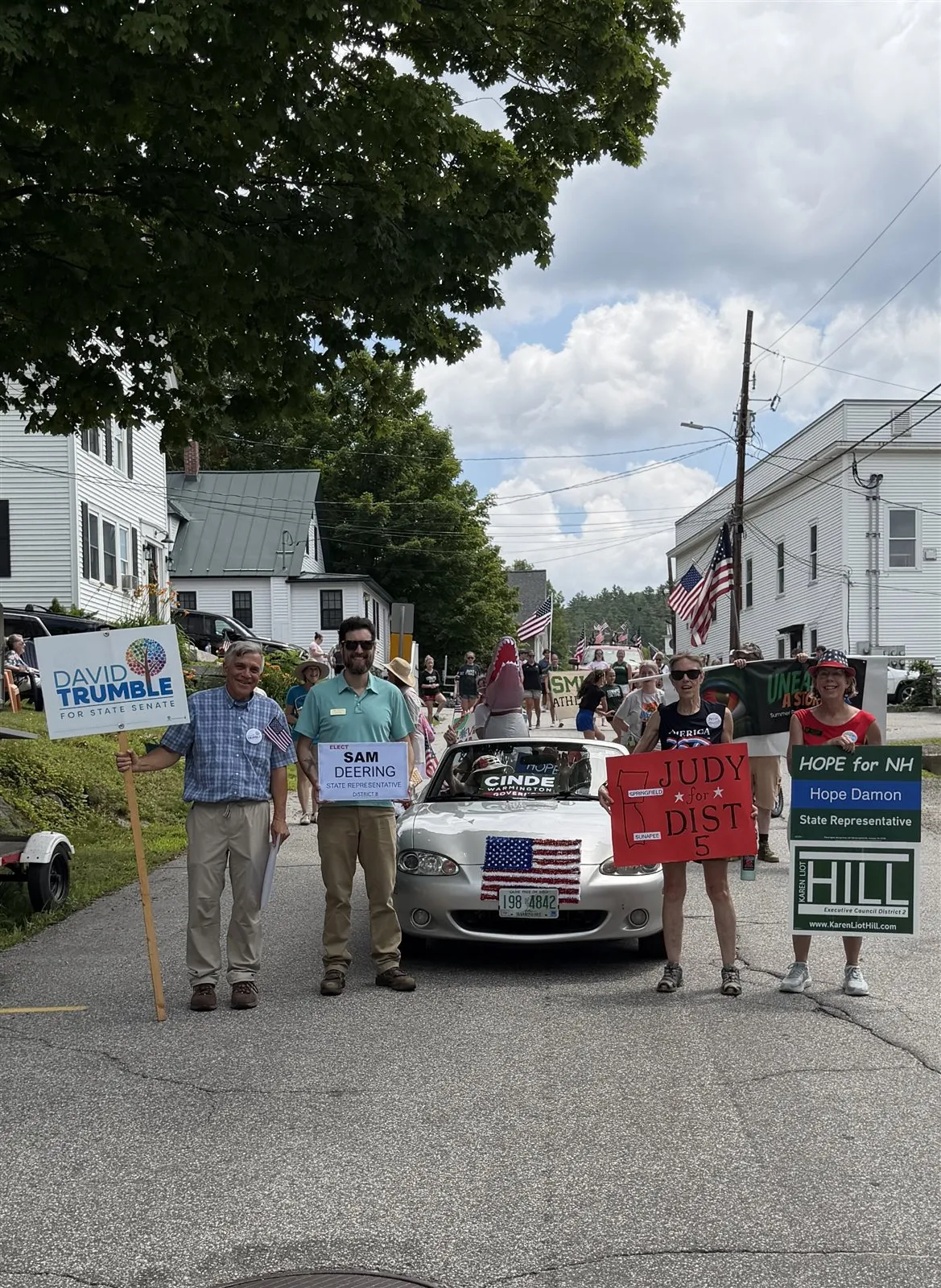 Sam Deering marching in a small-town parade holding an Elect Sam Deering sign